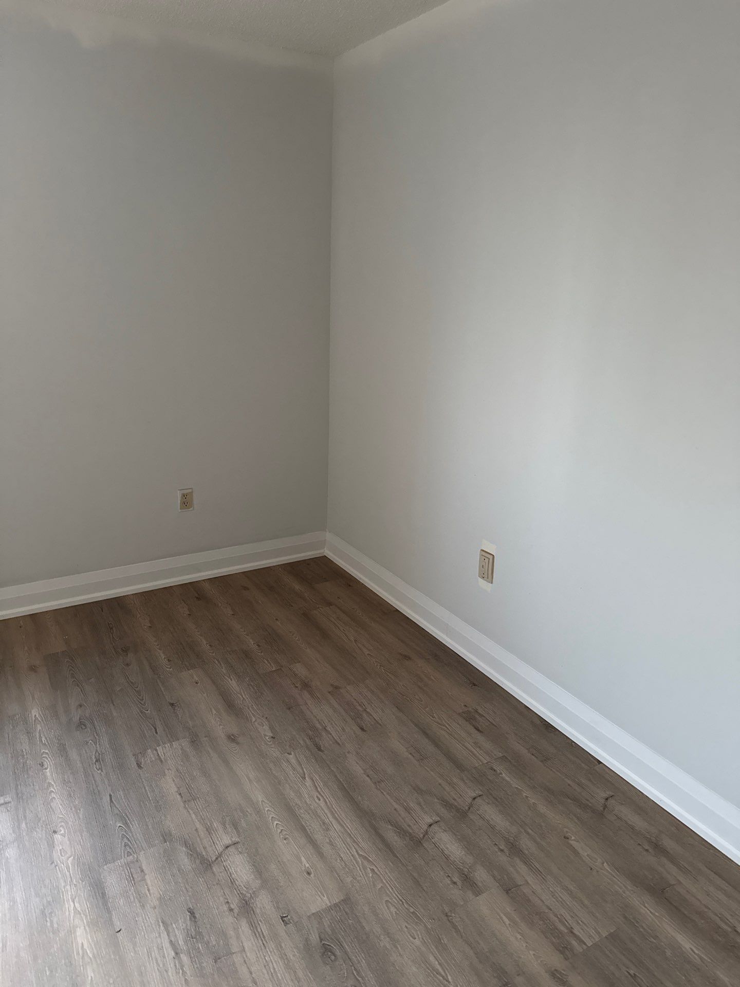 Close view of SmartDrop 7 Cashmere vinyl plank flooring with white baseboards